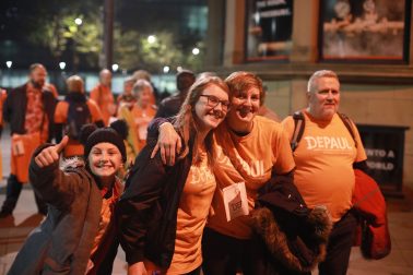 group of people in orange Depaul T-shirts walking at night