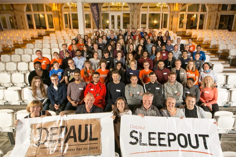 Birds eye view of Depaul staff in a hall. The people are holding signs that read 'Depaul' and 'Seepout'