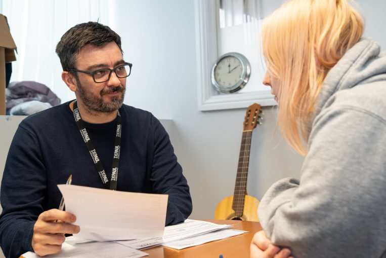 Man with glasses talking to young woman with blonde hair