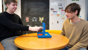 Two young men playing connect 4 in a shared kitchen