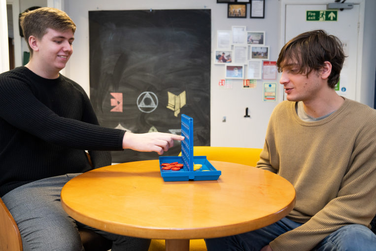 Two young men playing connect 4 in a shared kitchen