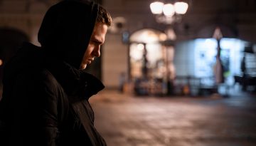 Young man with hood up in black parka coat