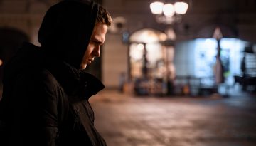 Young man with hood up in black parka coat