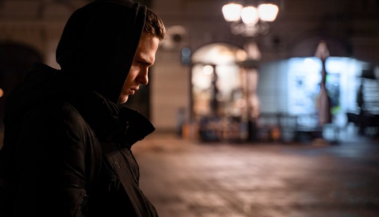 Young man with hood up in black parka coat