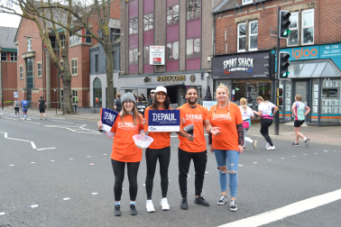 Four running supporters wearing orange Depaul t-shirts smiling