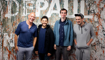 Depaul's CEO with a group pf young people standing in front of a wall with the Depaul logo on it