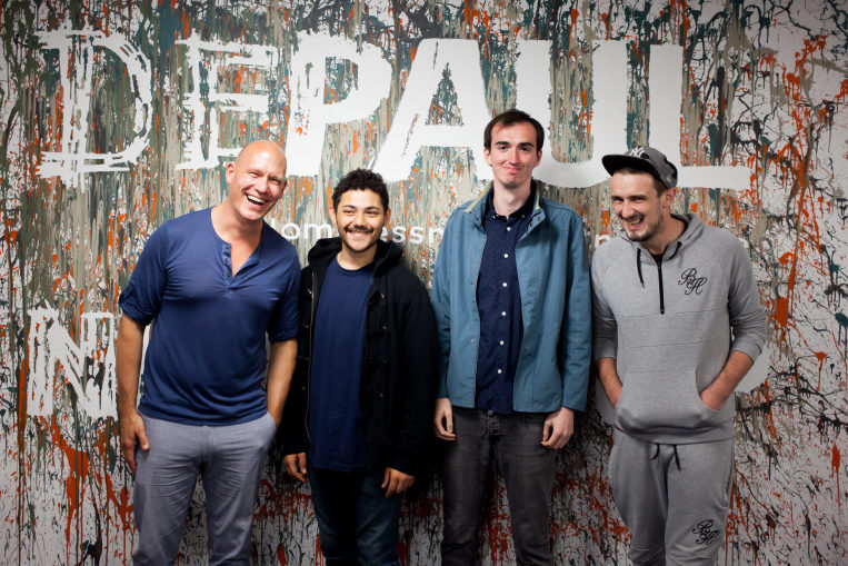 Depaul's CEO with a group pf young people standing in front of a wall with the Depaul logo on it