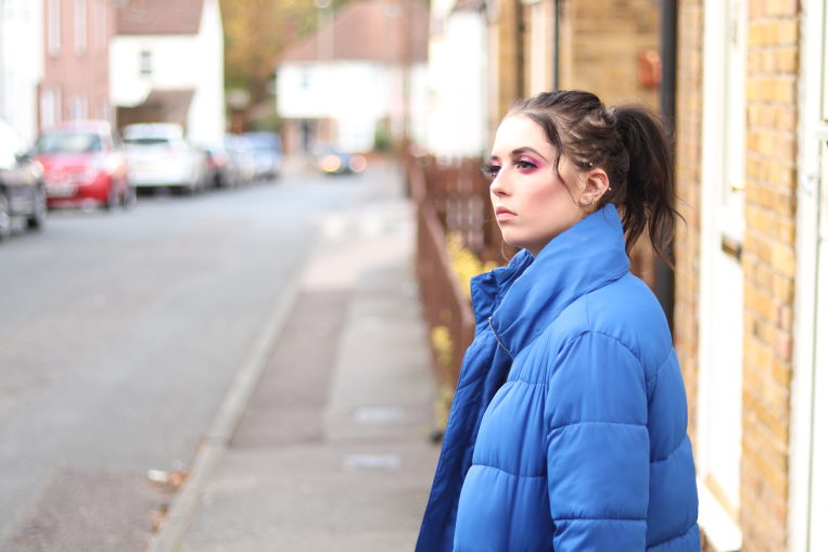 Woman in blue puffa jacket standing on the street