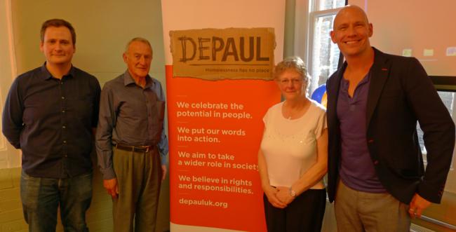 Depaul staff standing on front a Depaul banner smiling