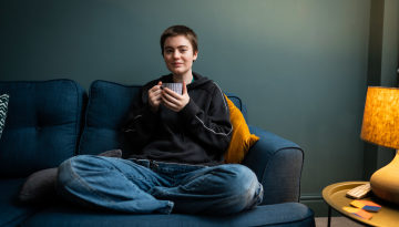 Young person sitting on the sofa drinking from a mug