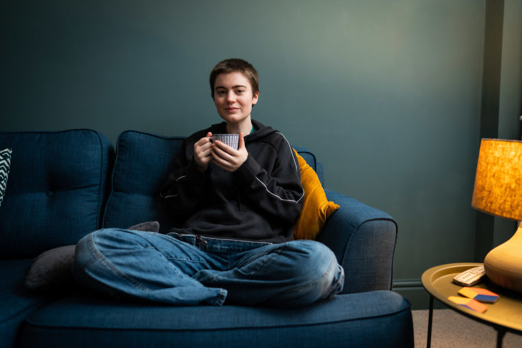 Young person sitting on the sofa drinking from a mug