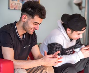 Two young men sat a sofa side by side