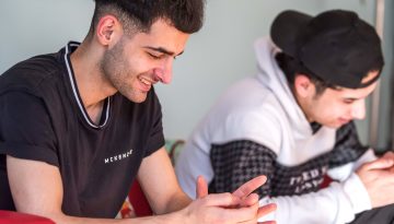 Two young men sat a sofa side by side