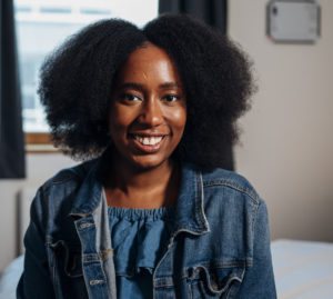 Ruth sitting on a bed smiling