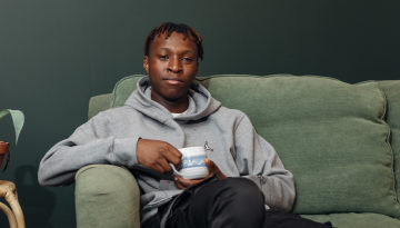 Young man sat on a sofa holding a cup of tea