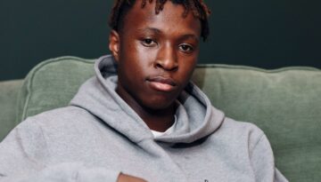 Young man holding a cup of tea looking to the camera.
