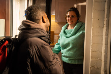 Volunteer host opening the door to a young person
