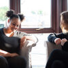 Two young women sitting on sofa talking and laughing