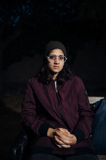 Young woman sat in the cold on a bench