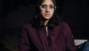 Young woman sat in the cold on a bench