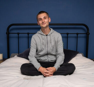 Young person on a bed smiling looking content