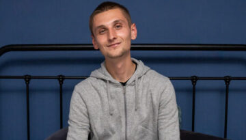 Young person on a bed smiling looking content