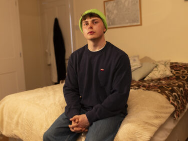 Jamie sitting on a bed in a hosts home