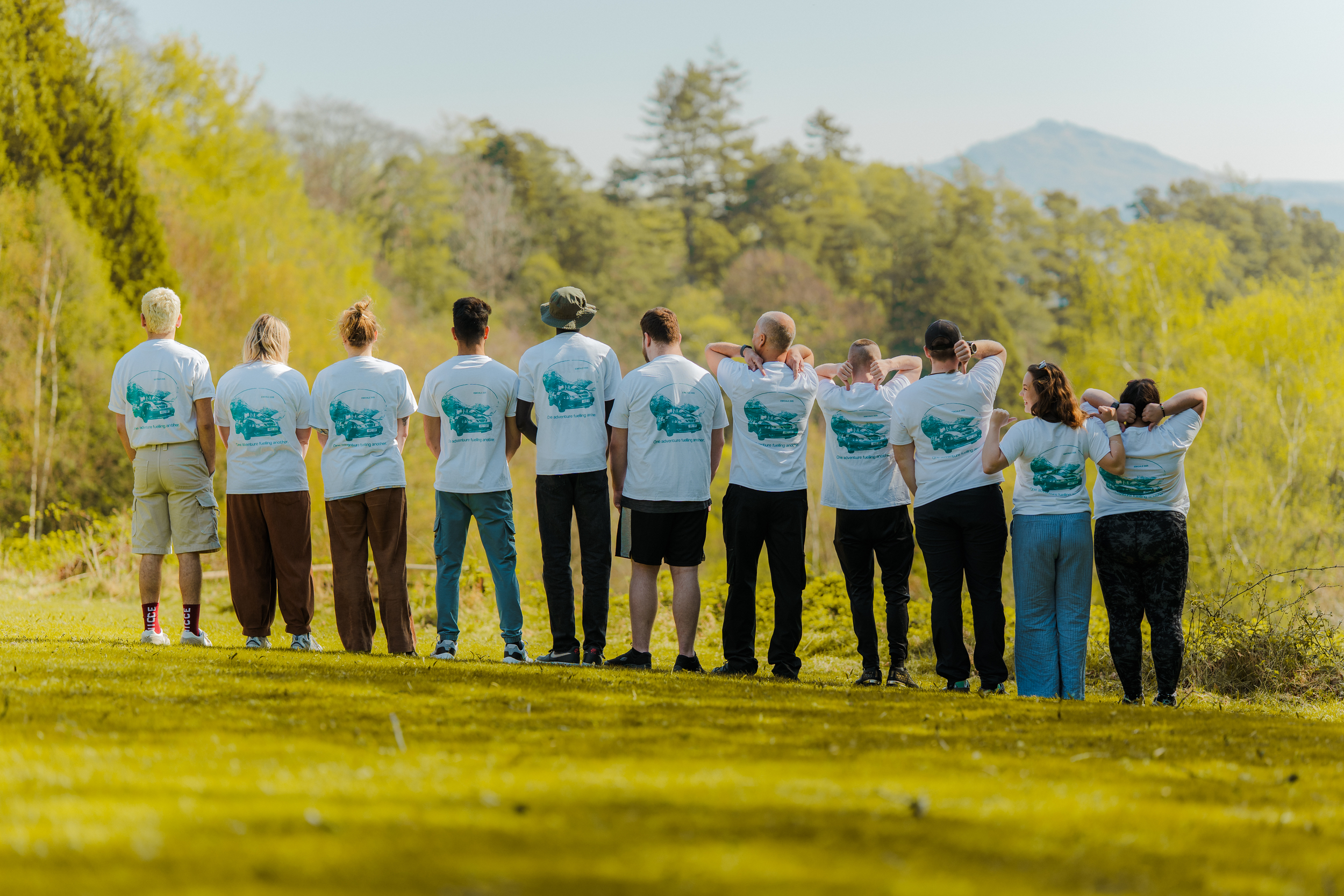 Group of young people stood in a line with their backs to the camera.
