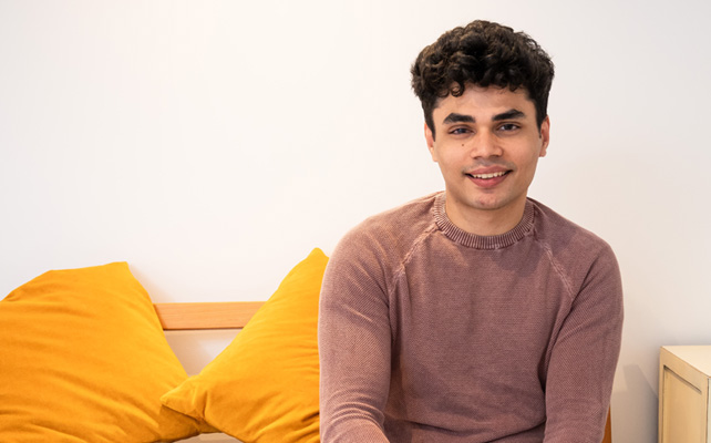 Young male 'Mo' sitting on a bed