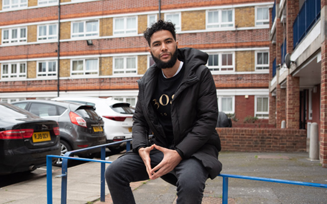 Man sitting on wall next to flats