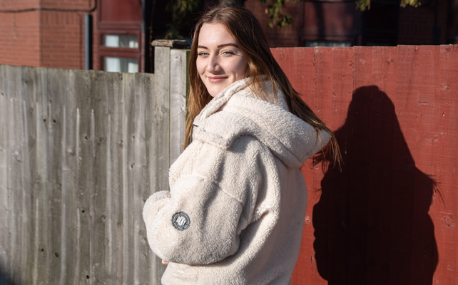 Girl in street next to red wall