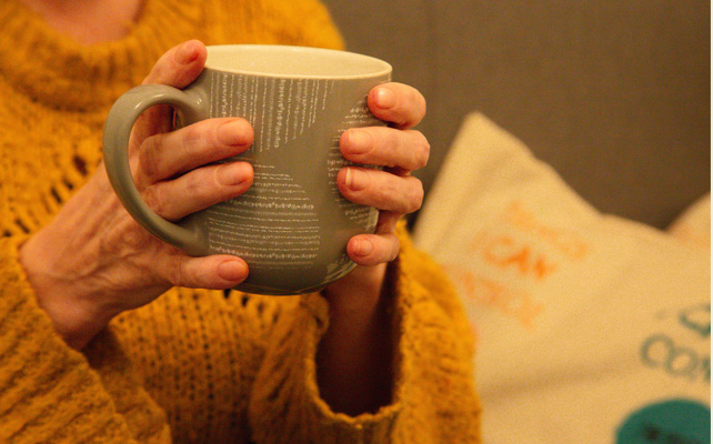 Older woman's hands on mug