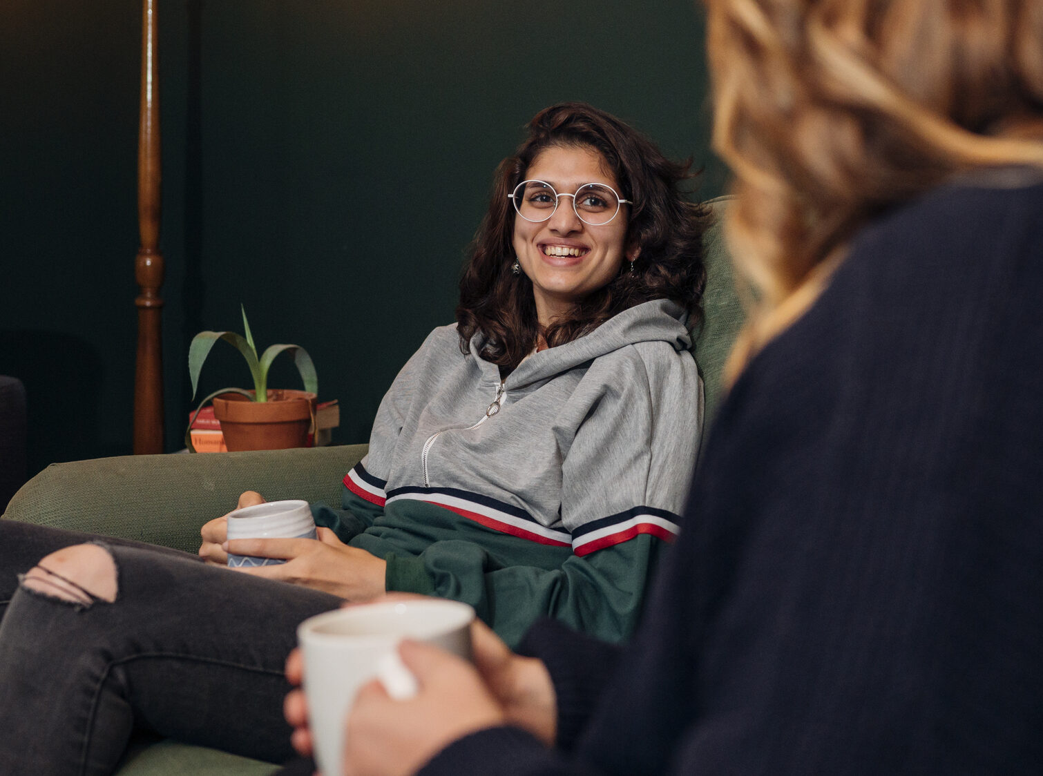 young person smiling with volunteer host in a living room