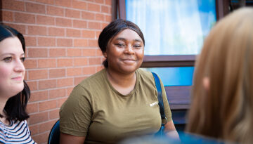 young person sat in a garden with Depaul UK staff
