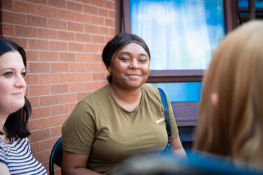 young person sat in a garden with Depaul UK staff