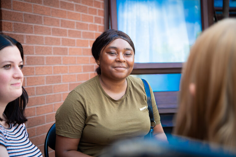 young person sat in a garden with Depaul UK staff
