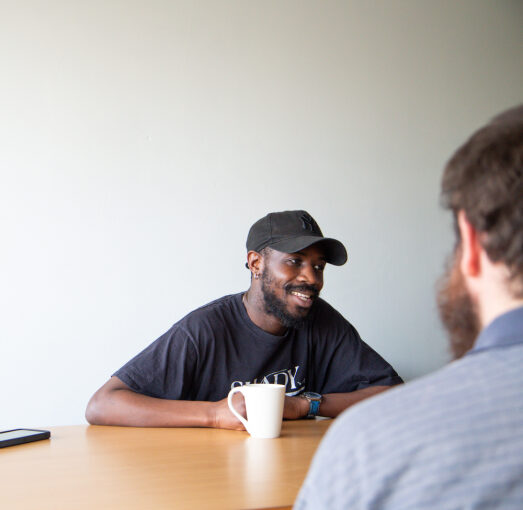 Depaul UK staff member smiling talking to a young person with their back to the camera