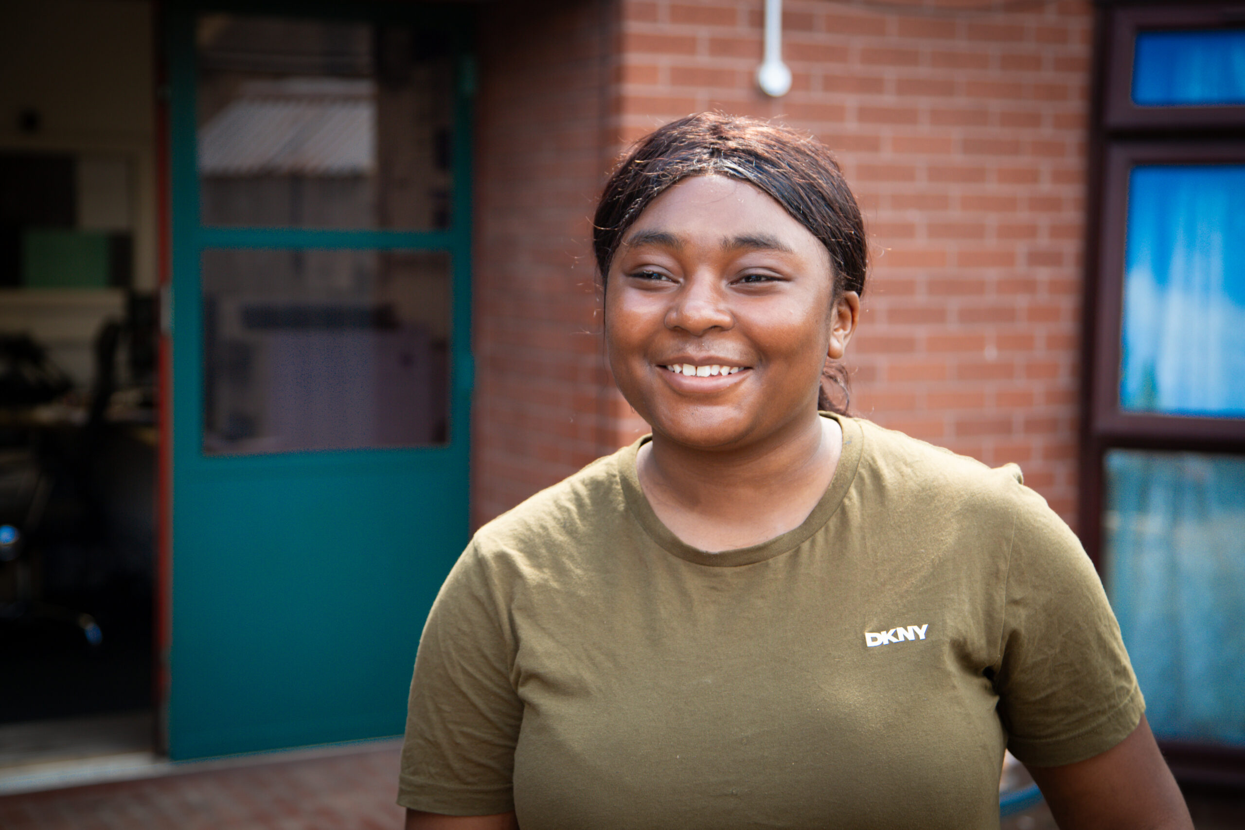 young black woman smiling to camera stood in the sunshine