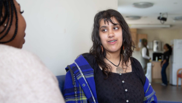 young girl and Depaul UK staff sat on a sofa in supported accommodation service