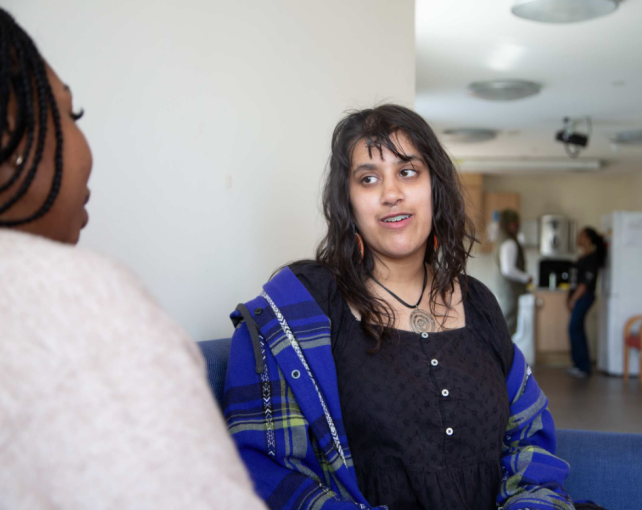 young girl and Depaul UK staff sat on a sofa in supported accommodation service