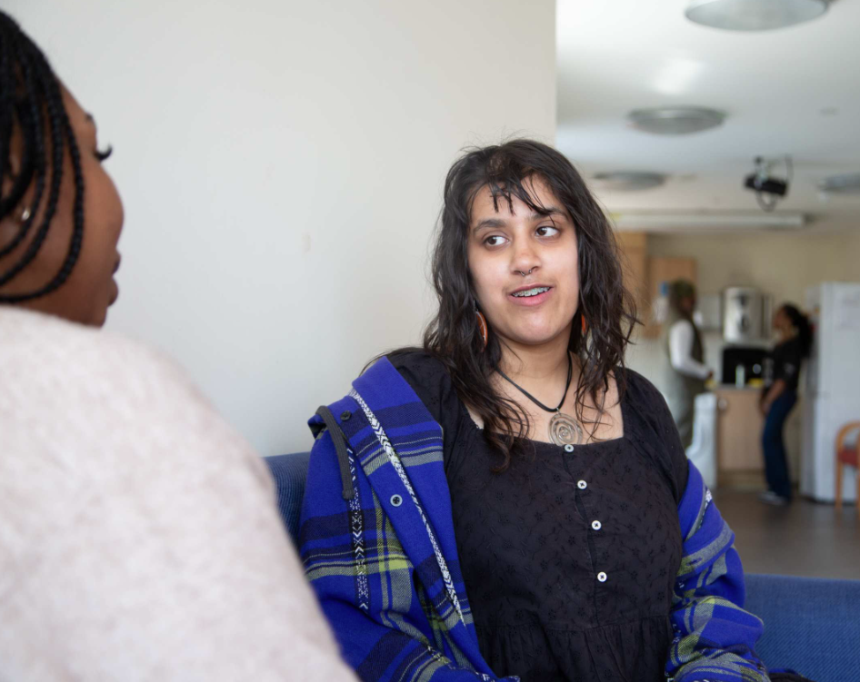 young girl and Depaul UK staff sat on a sofa in supported accommodation service