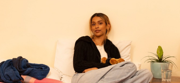 Kassi sat on a hosts bed holding a teddy bear
